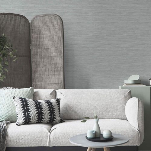 Room shot of the Deeply Textured Grasscloth Wallpaper Grey installed in a living room with couch and coffee table in foreground