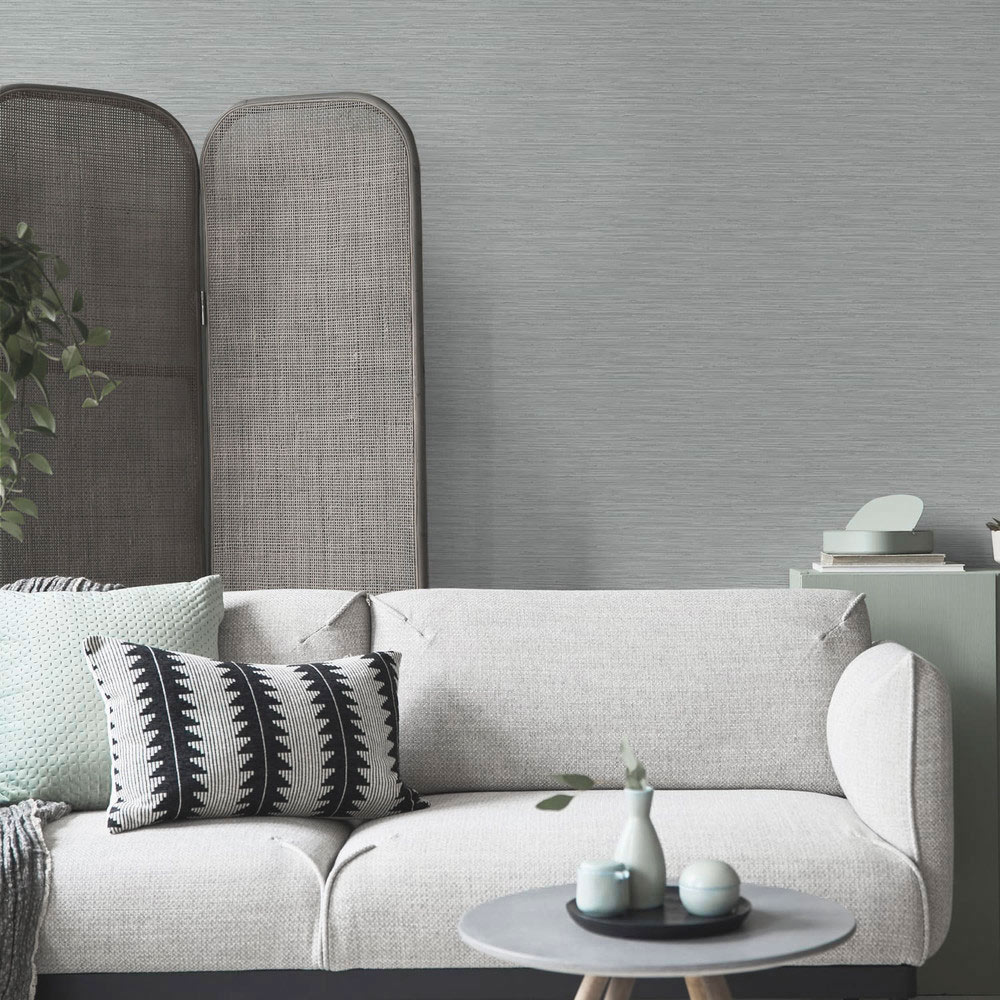 Room shot of the Deeply Textured Grasscloth Wallpaper Grey installed in a living room with couch and coffee table in foreground