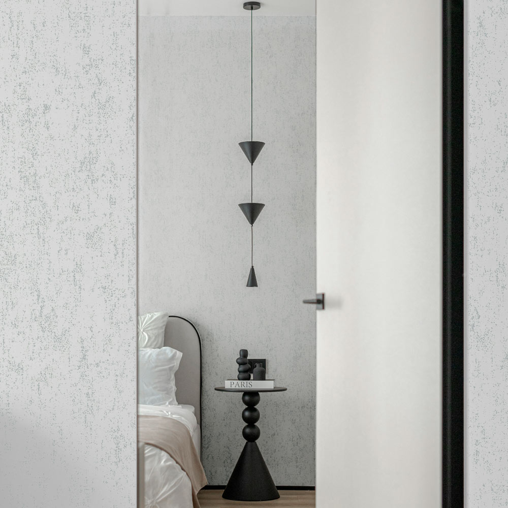Hotel room door opening onto bedroom with Metallic Silver Grey Mineral Plaster Wallpaper on the walls. Also shows a bed, table and pendant light fitting.