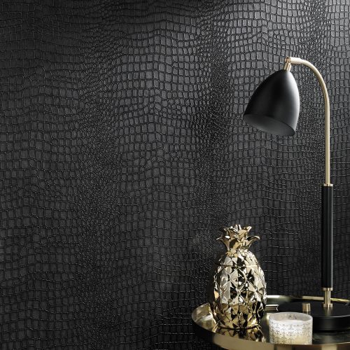 Crocodile Wallpaper Black installed onto a lounge wall. Foreground is the top of a table with gold lamp and gold pineapple