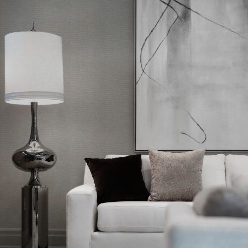 Lounge with Crocodile Wallpaper Grey installed on wall. Foreground features a couch with cushions and a sculptural modern lamp.