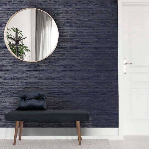 Entrance hall with metallic grasscloth sapphire wallpaper on wall - also features a round mirror, blue velvet bench and pillow