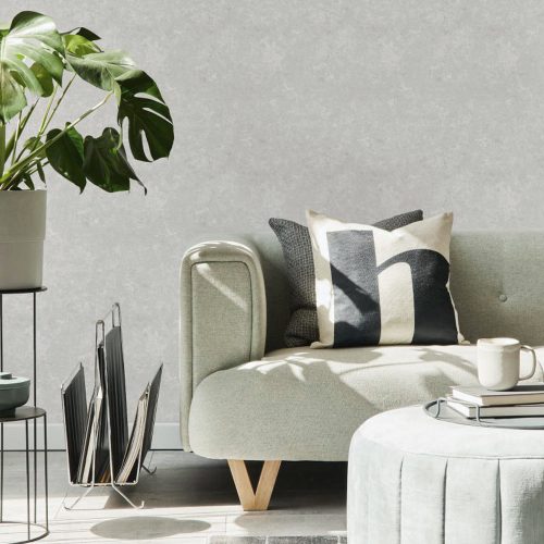 Lounge with Textured Plaster Wallpaper in Off White installed onto walls. The foreground contains a light sage green counch, ottoman table, plant on stand and magazine holder.