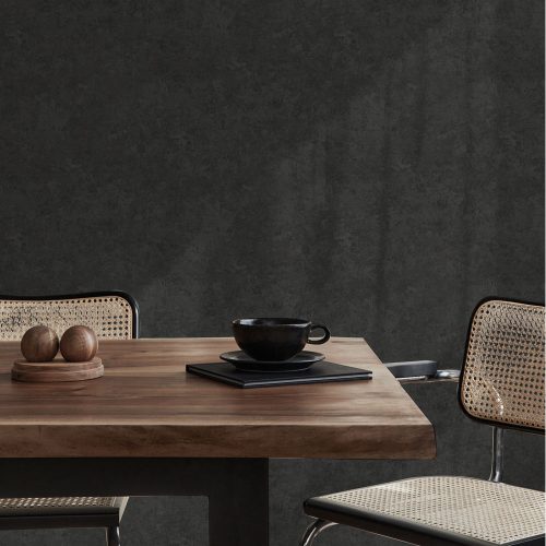 Dining room with Textured Plaster Wallpaper Black installed on walls with sunlight streaming through a window. Foreground is a wooden table with coffee cup and 2 chairs.