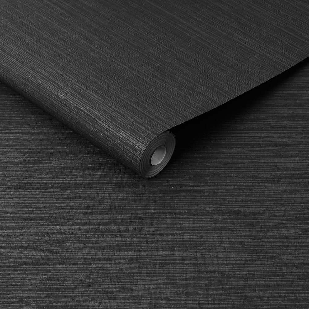 Roll of black faux grasscloth wallpaper in black, slightly unrolled with the same wallpaper in the background