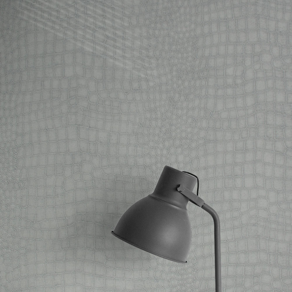 Charcoal lamp casting a shadow on the textures of the grey crocodile wallpaper