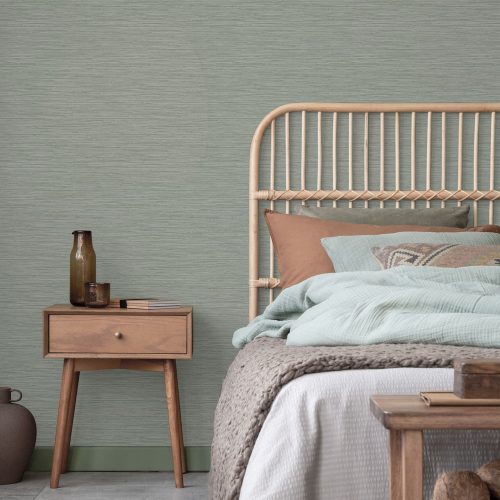Bedroom with a cane bed and wooden side table - with the Deeply Textured Grasscloth Wallpaper Sage installed on the wall