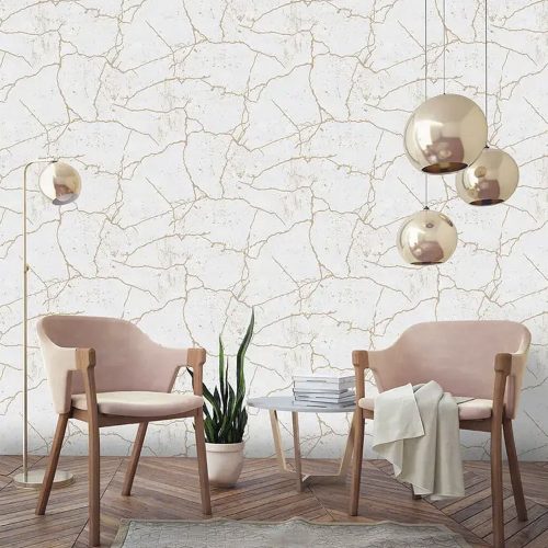 Styled lifestyle shot with Kintsugi Wallpaper Metallic Gold installed on the wall. Also features a trio of gold bulb pendant light, a standing lamp, 2 upholstered chairs, side table and floor pot plant