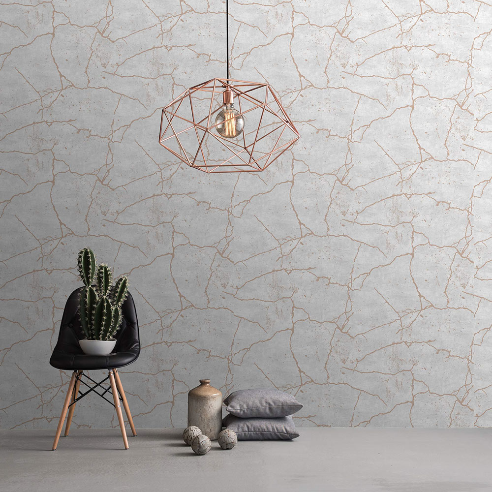Styled room with the Kintsugi Wallpaper Rose Gold installed on the wall. Also features rose gold geometric metal pendant light, cactus on black cafe chair with pillows and ceramic on the floor