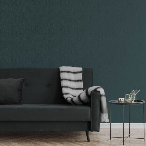 Lounge with metallic draped silk wallpaper emerald green installed on the wall. Also shows a dark grey couch with striped throw and metal side table with plant and gold paperweight
