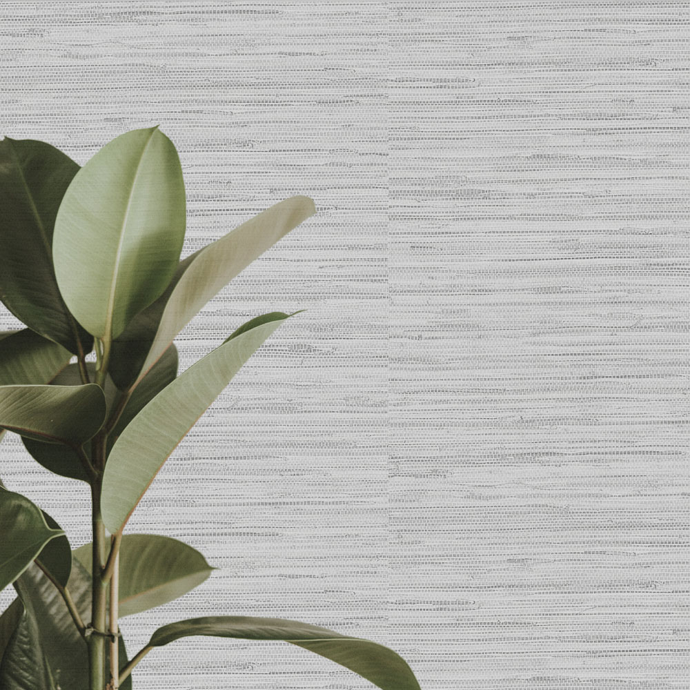 Close up of the installed pearlescent silver faux grass cloth wallpaper, also shows leafy plant in the foreground