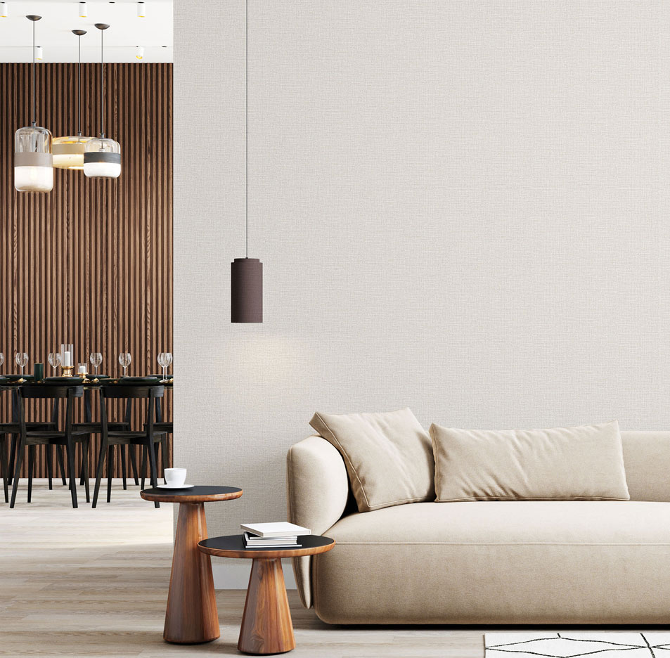 Lounge with textured woven wallpaper installed on the wall. On the left is a dorr-opening with a dining room with slat wallpaper. The foreground shows a cream couch, pendant light and 2 styled modern side tables